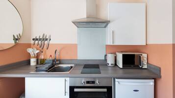 A compact kitchen with a sink, stove, microwave, and oven.