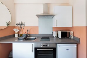Une cuisine de taille réduite équipée d’un évier, d’une cuisinière, d’un four à micro-ondes et d’un four traditionnel.
