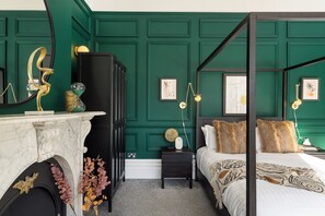 Une chambre à coucher avec un lit à baldaquin, une cheminée en marbre et des murs recouverts de panneaux de bois peints en vert.
