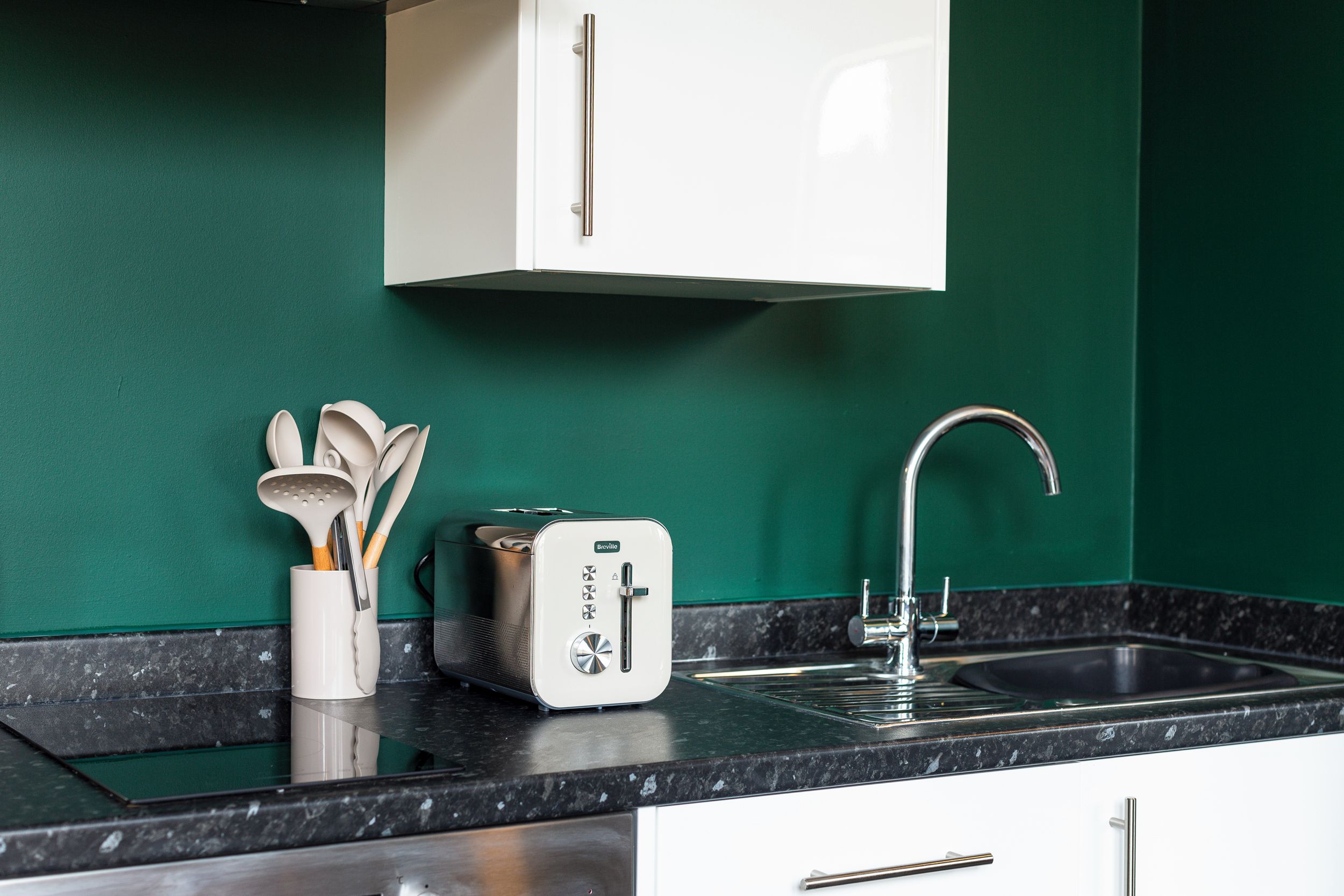 A kitchen with a white cabinet, a toaster, and a sink.