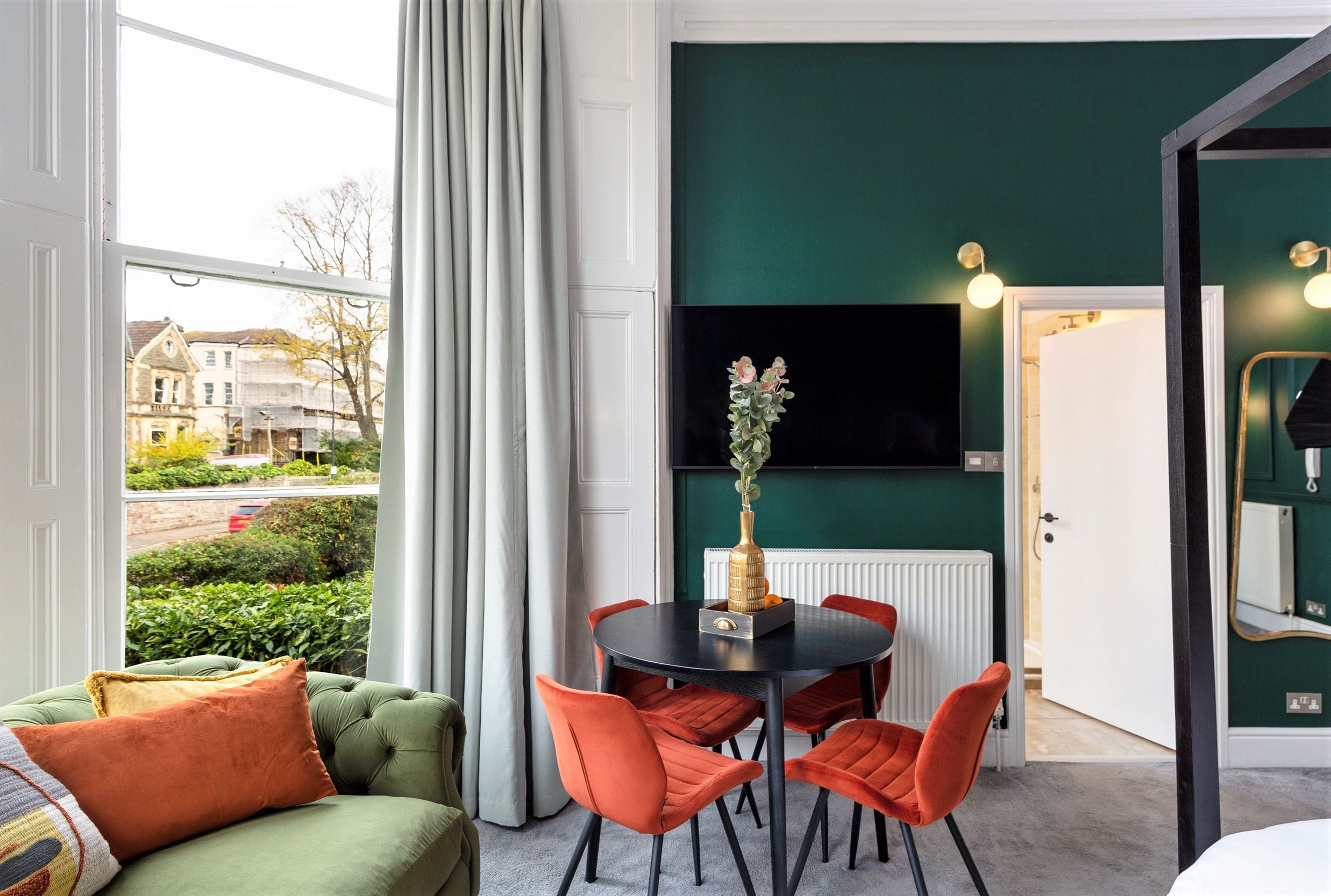 Une pièce comprenant une table à manger, des chaises, un canapé et un téléviseur fixé au mur.