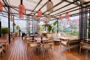 An outdoor seating area with wicker furniture, red hanging lamps, and a city view. - Radisson Serviced Apartments City Center (Antananarivo)