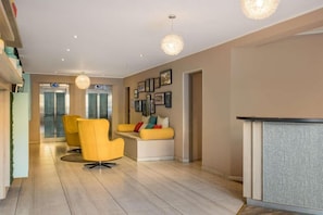 A modern lobby with a reception desk, seating area, and framed pictures on the wall.