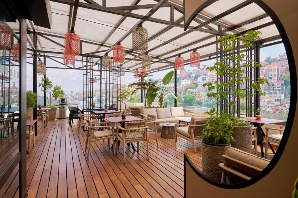 Una terraza en la azotea con suelo de madera, mobiliario de mimbre y farolillos rojos colgantes.