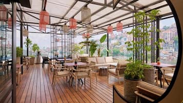Una terraza en la azotea con suelo de madera, mobiliario de mimbre y farolillos rojos colgantes.