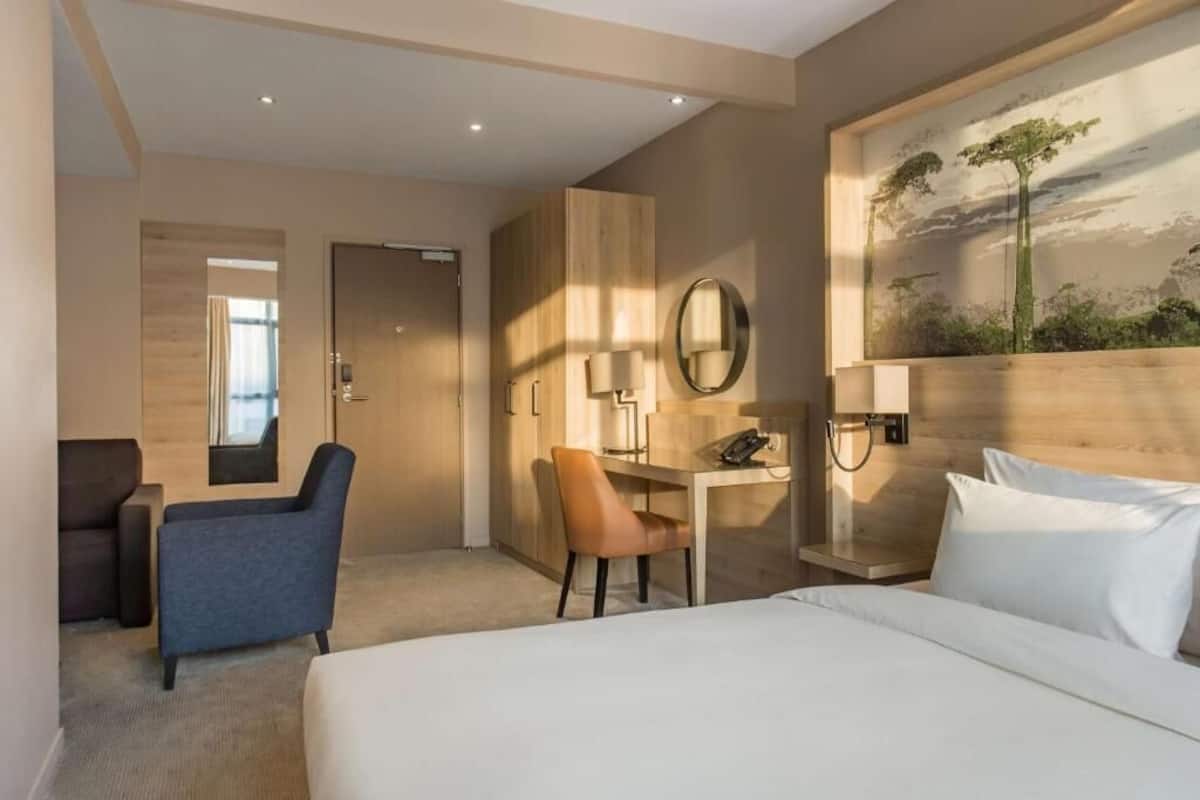 Ein Hotelzimmer mit einem Bett, einem Schreibtisch, einem Sessel, einer Couch und einem Bild an der Wand.