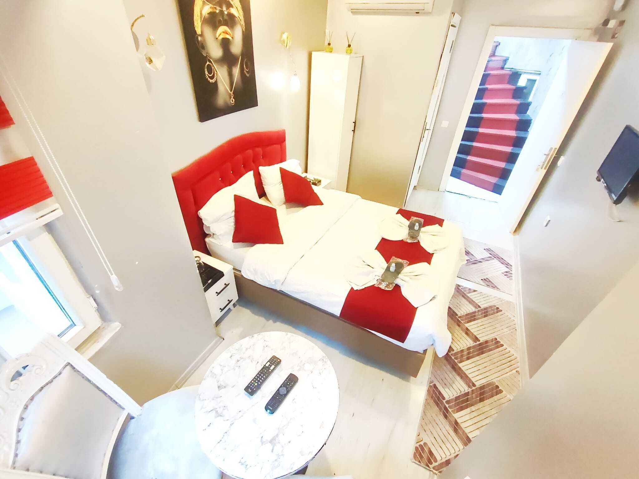 A hotel room with a bed, a round table, and a door with a red and blue striped pattern.