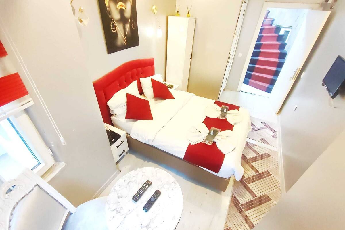 A hotel room with a bed, a round table, and a door with a red and blue striped pattern.
