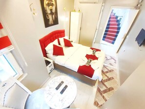 A hotel room with a bed, a round table, and a door with a red and blue striped pattern. - Taksim Capital Hotel (Istanbul)