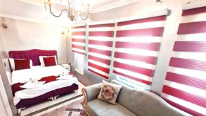 A hotel room with a bed, a sofa, a chandelier, and striped blinds. - Taksim Capital Hotel (Istanbul)