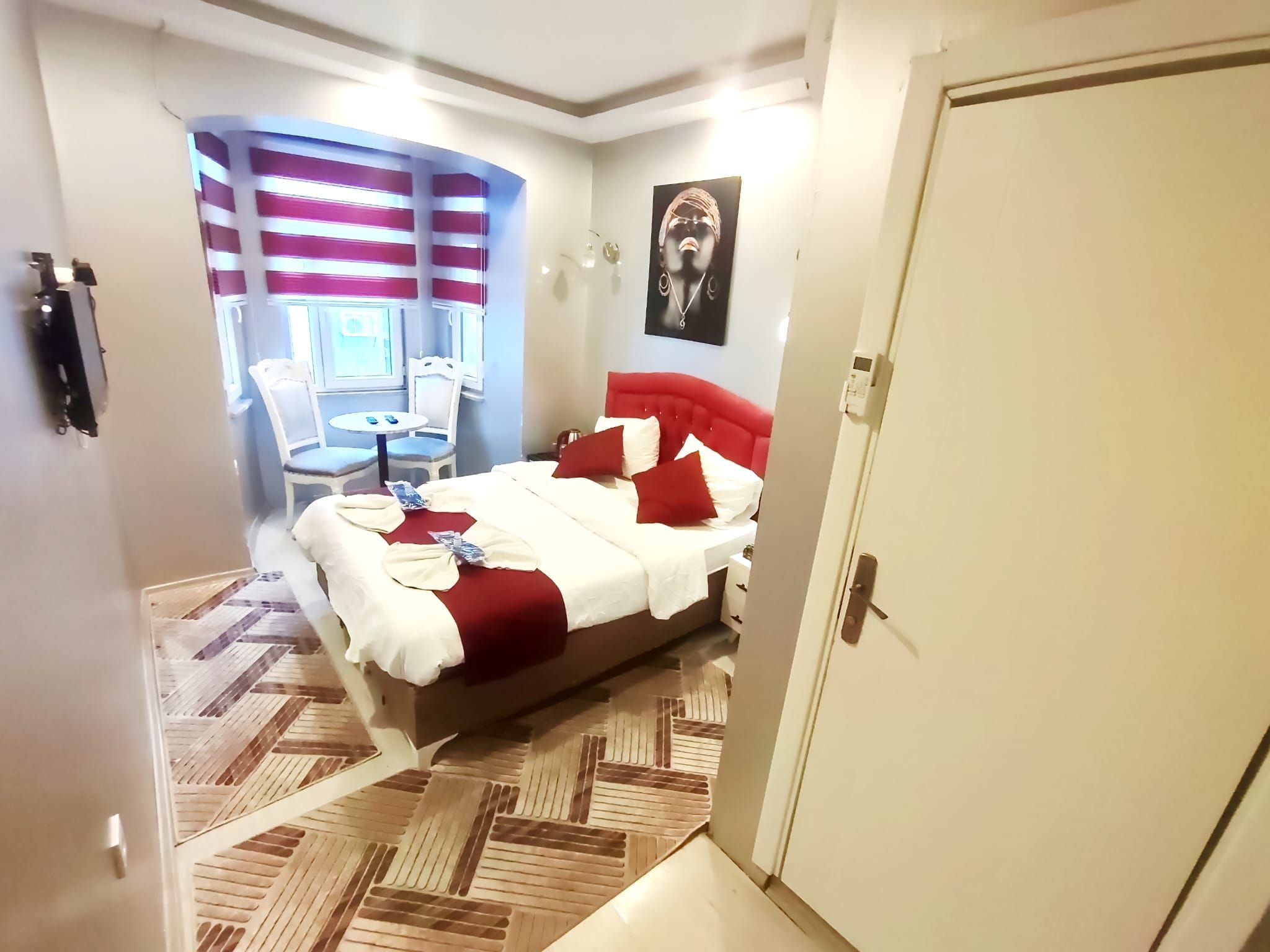 A hotel room with a bed, a chair, a small table, and a window with curtains.