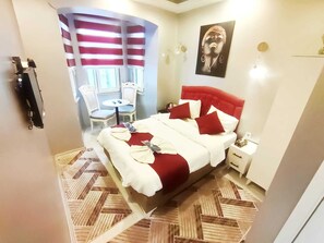 A hotel room with a large bed, a small table with chairs, a painting on the wall, and a patterned floor. - Taksim Capital Hotel (Istanbul)