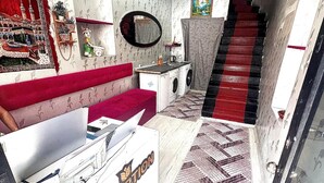 A compact living space with a red sofa, a white cabinet, a washing machine, and a staircase with a red carpet. - Taksim Capital Hotel (Istanbul)