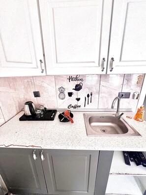 A kitchen with white cabinets, a granite countertop, and a sink. There are kitchen utensils and a coffee maker on the counter. - Taksim Capital Hotel (Istanbul)