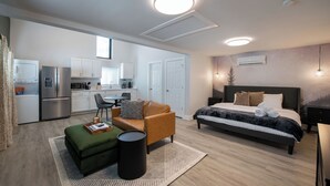 A modern apartment with a kitchenette, a bedroom with a large bed, and a living area with a sofa and coffee table. - Cozy Den - Minutes to Downtown Denver and near Red Rocks (Denver)