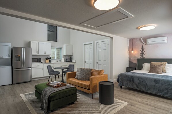 A modern, compact living space with a kitchenette, a sofa, a bed, and a trash can. - Cozy Den - Minutes to Downtown Denver and near Red Rocks (Denver)