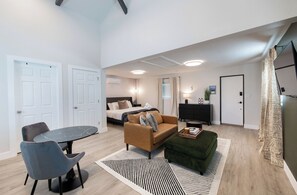 Une chambre d’hôtel moderne comprenant un lit, un canapé, une table à manger avec des chaises, une télévision et un petit bureau.