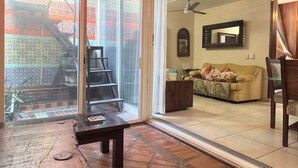 A spacious living area with a large sliding glass door leading to a balcony, a ceiling fan, and a wooden coffee table. - Casa Primavera (Puerto Vallarta)