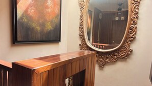 A wooden reception desk with a mirror above it, a framed painting on the wall, and a staircase with light-colored tiles. - Casa Primavera (Puerto Vallarta)