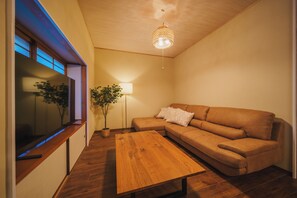 Uma sala de estar moderna com uma mesa de centro de madeira, um sofá marrom, um abajur e um lustre.