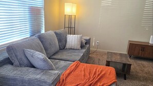 A modern living room with a grey sectional sofa, a floor lamp, and a small wooden table. - 3-bedroom townhome in pleasant Mesquite with AC for relaxing stays (Mesquite)
