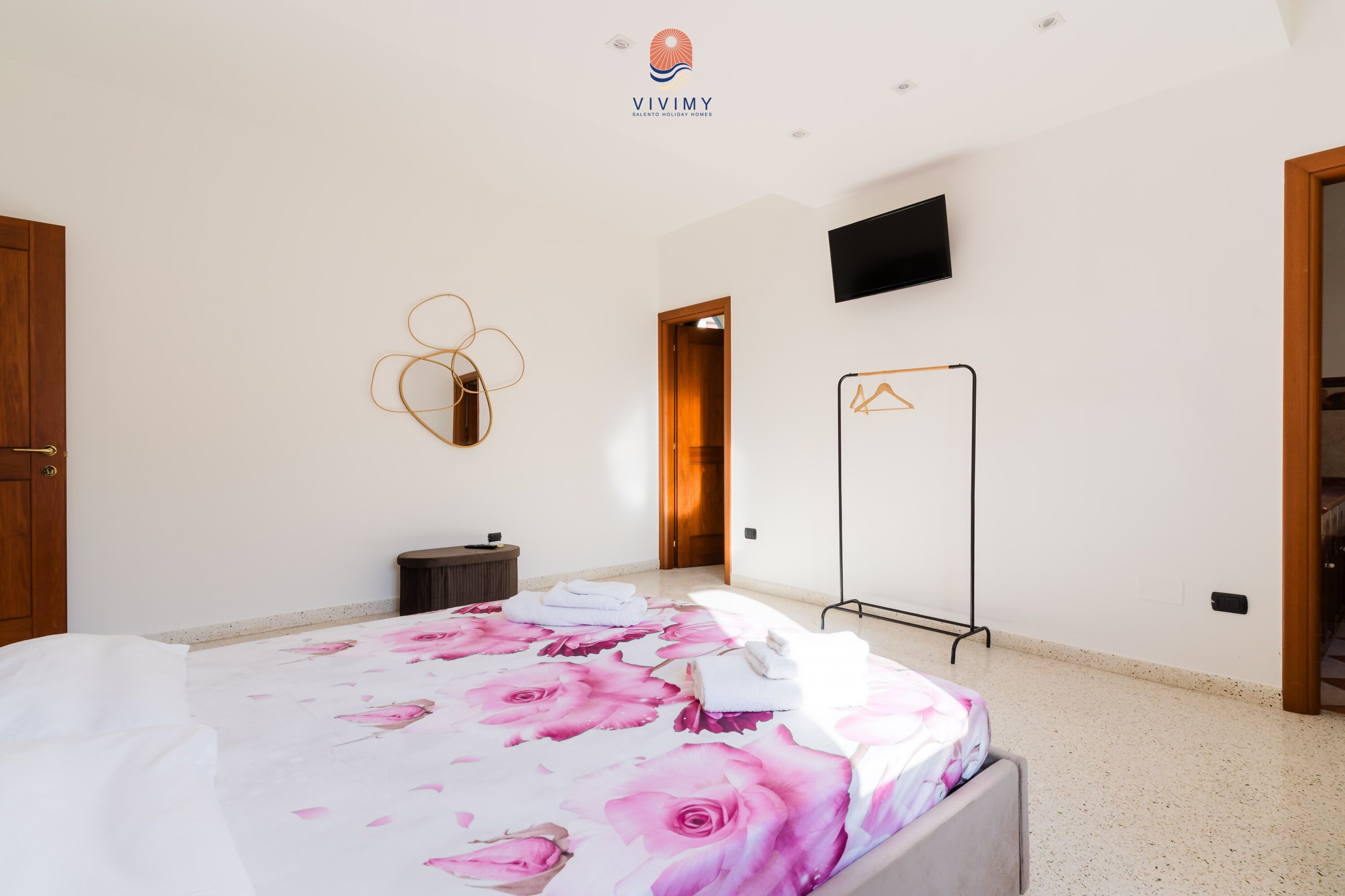 Ein Hotelzimmer mit Bett, Fernseher, Kleiderständer und Schrank.