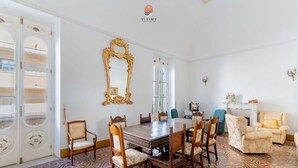A dining area with a wooden table and chairs, a large ornate mirror, and patterned floor tiles. - White Queen by Vivimy (Gallipoli)