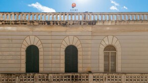 A building facade with three arched windows and a balcony with intricate railings. - White Queen by Vivimy (Gallipoli)