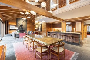 A spacious dining area with a long wooden table and chairs, a kitchen with a bar, and a fireplace. - Vail Village Walk to Ski, 12ppl, Sebastian Access (Vail)