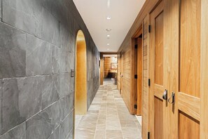 A hallway with dark stone walls, wooden doors, and a tiled floor. - Vail Village Walk to Ski, 12ppl, Sebastian Access (Vail)