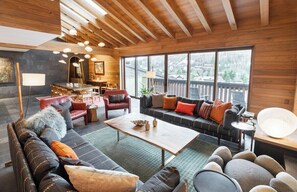 A spacious living area with a wooden ceiling, large windows, and a mix of seating arrangements including sofas and chairs. - Vail Village Walk to Ski, 12ppl, Sebastian Access (Vail)