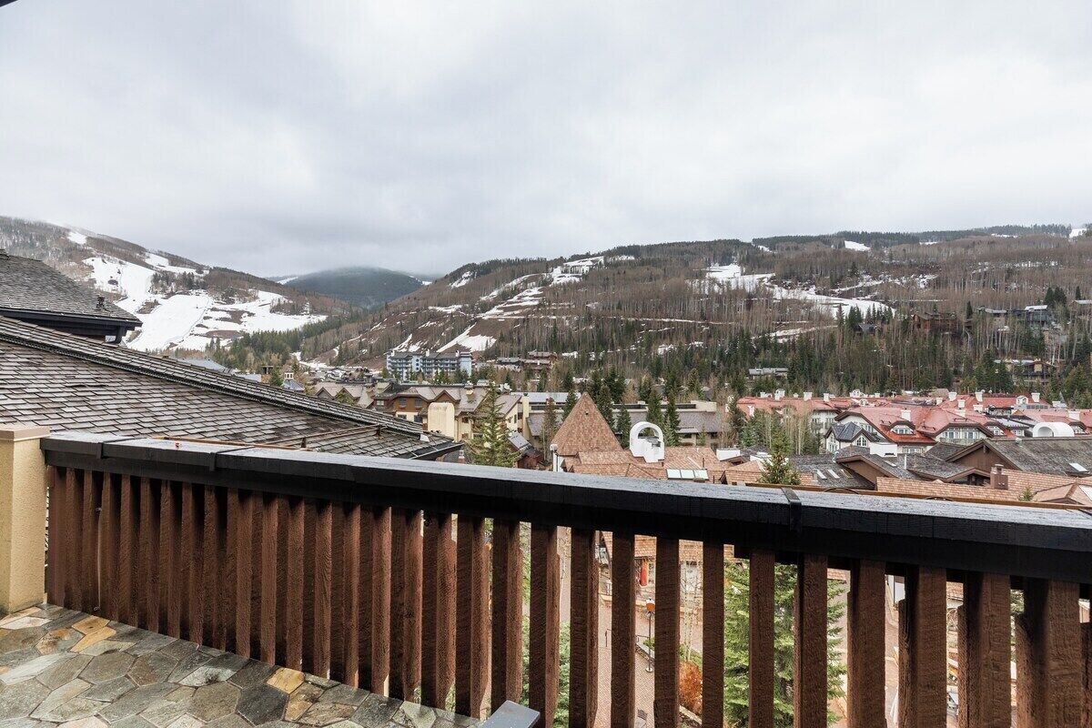 A residential area with houses, a wooden fence, and a mountainous backdrop.