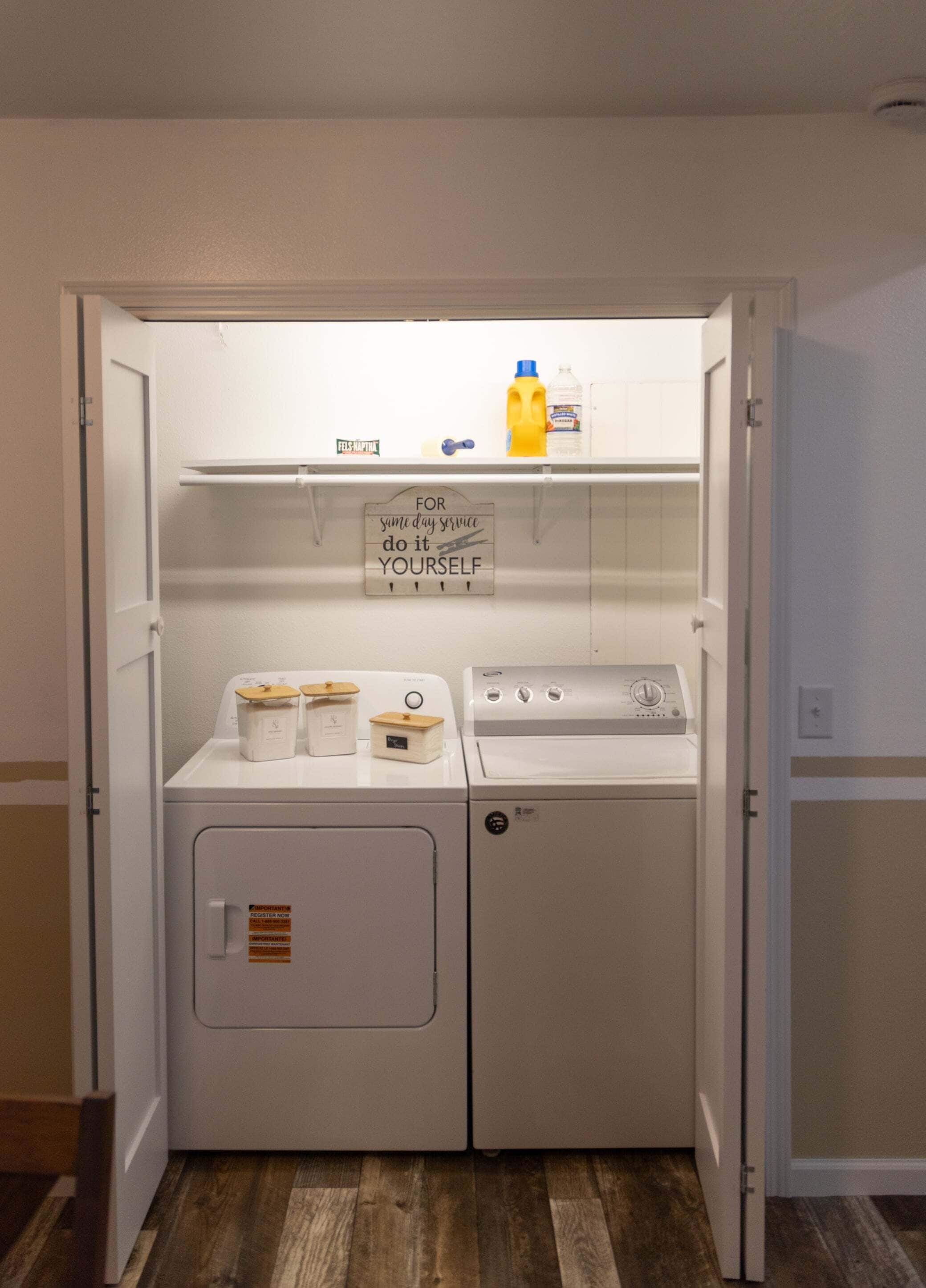 A laundry room with a washing machine, dryer, and detergent bottles on the shelves.