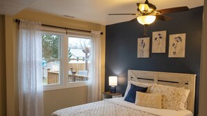 A bedroom with a bed, a nightstand, a ceiling fan, and a window with curtains. - Mimosa Bungalow - Mimosa Bungalow (Crane)