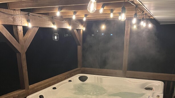 A hot tub with steps leading up to it, surrounded by wooden decking and a wooden ceiling. - Mimosa Bungalow - Mimosa Bungalow (Crane)