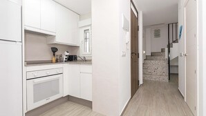 Een moderne keuken met witte kasten, een inbouwoven en een aanrecht met een koffiezetapparaat en andere apparaten.