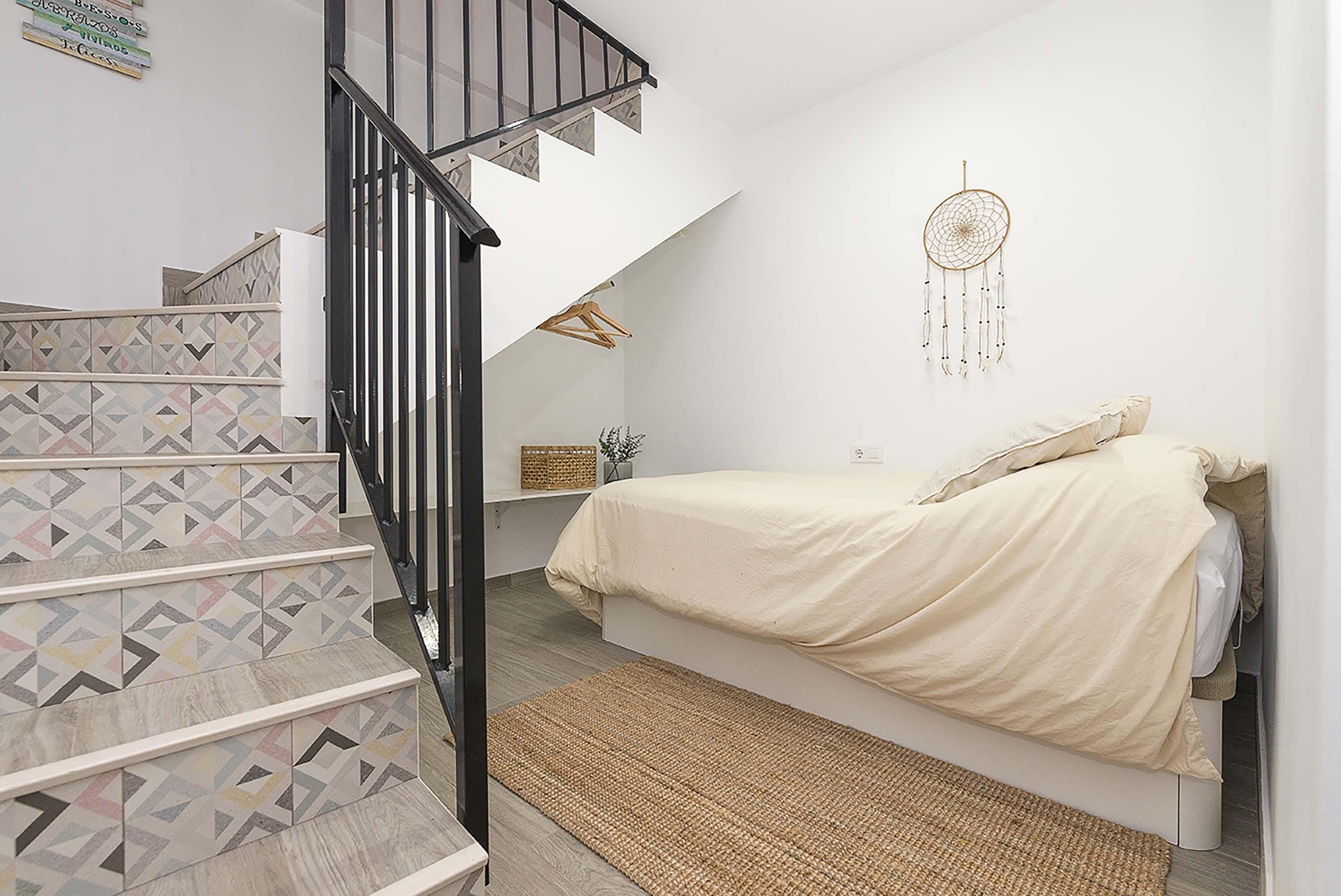 Ein Schlafzimmer mit einem Bett, einer Treppe und einem Traumfänger an der Wand.