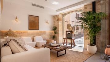 Una sala de estar moderna con un sofá, sillones, una mesita de centro y una planta grande en maceta.