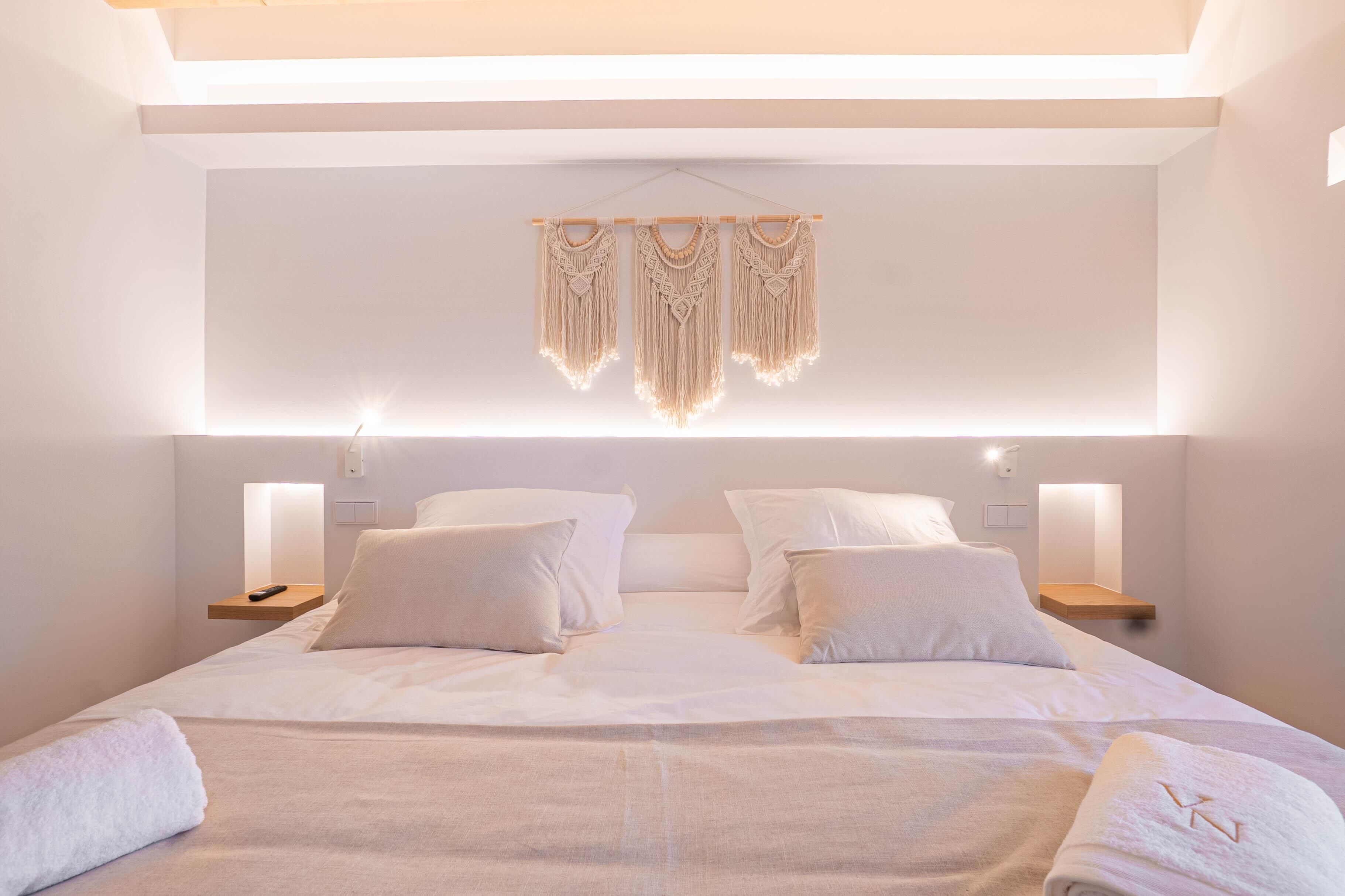 Une chambre d’hôtel moderne avec un grand lit, deux tables de chevet et une décoration murale en macramé.