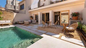 Un espace piscine extérieur moderne, doté d’une piscine à eau claire, de carreaux en pierre et de mobilier d’extérieur.