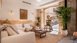 Un salon moderne avec un canapé, des fauteuils, une table basse et une grande plante en pot.