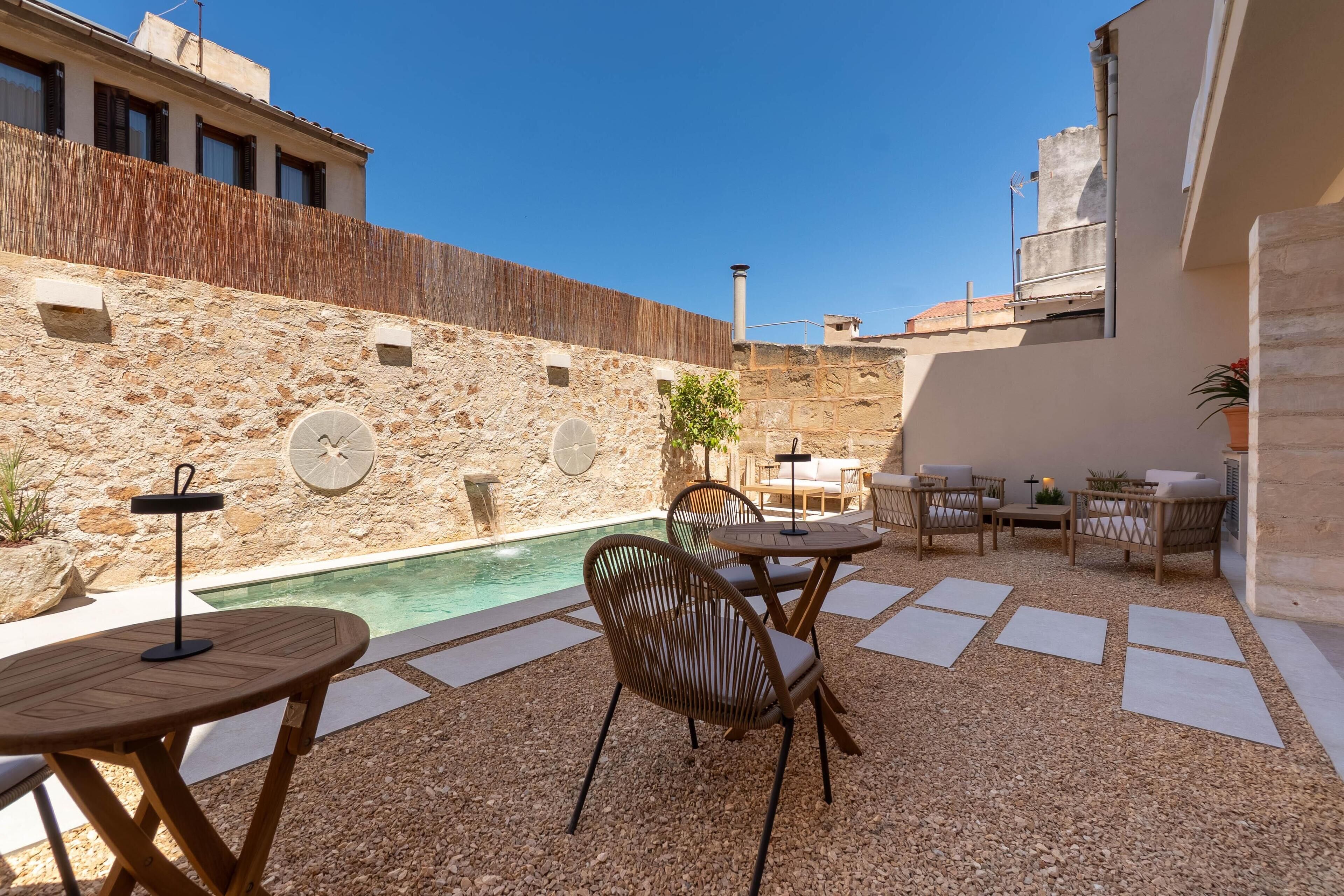 Un patio al aire libre con piscina, paredes de piedra y mobiliario exterior.