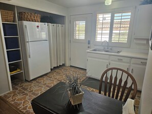 A compact kitchen with a refrigerator, a sink, and a dining area with a table and chairs.