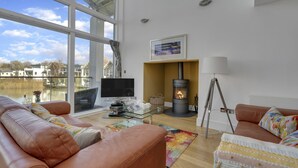 Una sala de estar con sofá, televisor, chimenea y vista al lago.
