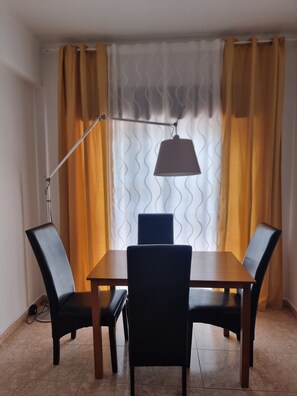 A dining area with a table and four chairs, a floor lamp, and curtains. - Happy House Central Apartment (Faro)