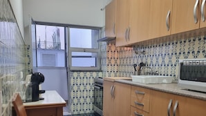 A kitchen with wooden cabinets, a sink, and a window. - Happy House Central Apartment (Faro)