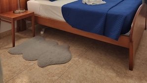 A neatly arranged hotel room with a bed, two bedside lamps, a grey rug, and a framed picture on the wall. - Happy House Central Apartment (Faro)