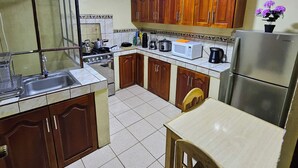 Une cuisine de taille réduite, dotée de meubles en bois, d’un évier, d’une cuisinière, d’un four à micro-ondes et d’un réfrigérateur.