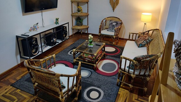 Un salon doté d’un téléviseur à écran plat, de meubles en osier, d’une table basse et d’une décoration murale.