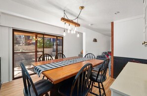 Ein Essbereich mit einem Holztisch und Stühlen, einer karierten Tischdecke und einer Pendelleuchte.